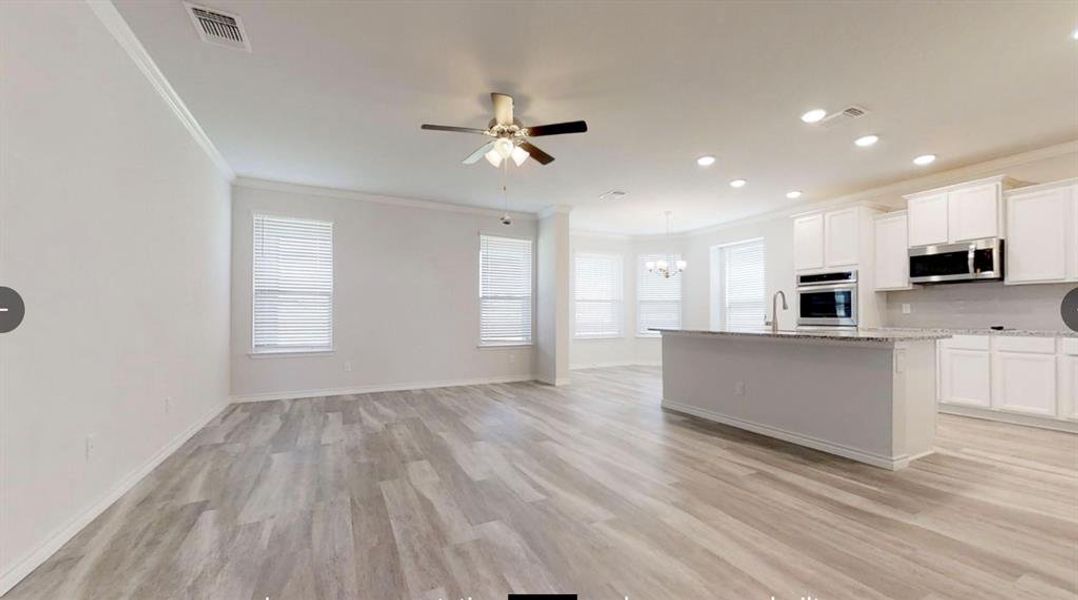 Kitchen featuring stainless steel appliances, crown molding, open floor plan, a chandelier, and a sink