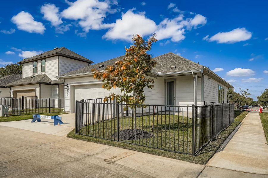 View of front of home featuring a garage, concrete driveway, a shingled roof, and a fenced front yard