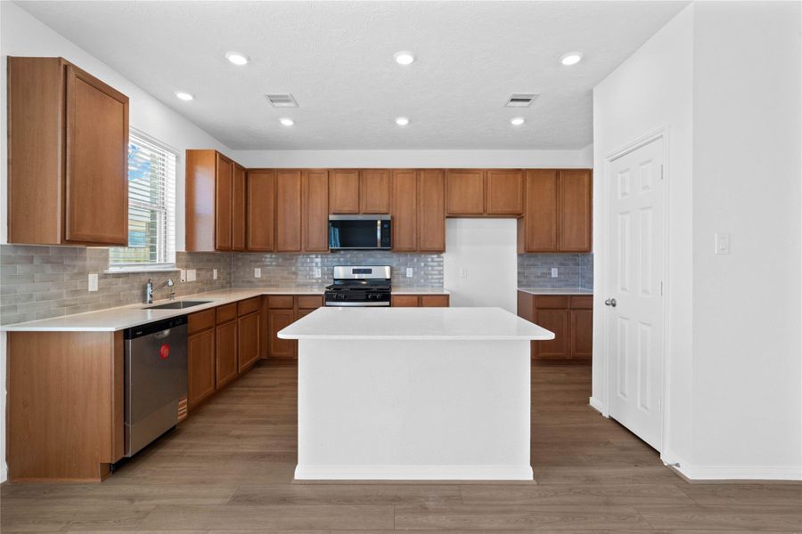 This bright and stylish kitchen showcases a spacious island with sleek Silestone countertops, perfect for both cooking and gathering. Woodmont Cody cabinetry and a modern tile backsplash add charm and functionality. This bright and stylish kitchen showcases a spacious island with sleek Silestone countertops, perfect for both cooking and gathering. Woodmont Cody cabinetry and a modern tile backsplash add charm and functionality.