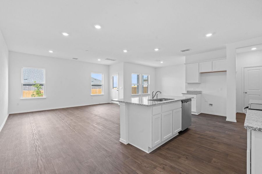 Kitchen with white cabinets, recessed lighting, light stone counters, dark wood finished floors, and an island with sink Kitchen with white cabinets, recessed lighting, light stone counters, dark wood finished floors, and an island with sink