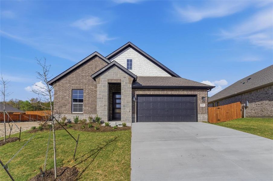 View of front facade with stone siding, concrete driveway, a gate, brick siding, and a garage