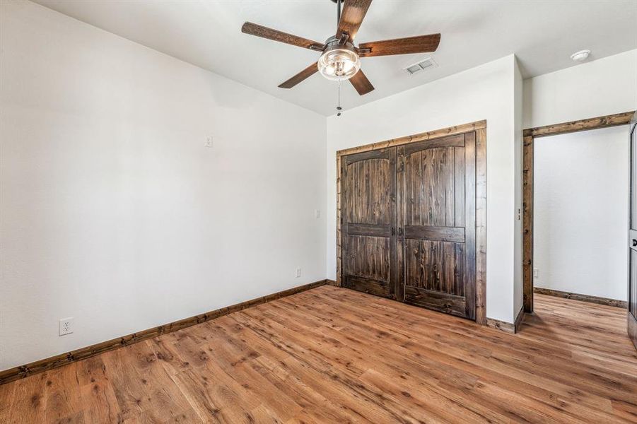 Unfurnished bedroom with a closet, baseboards, visible vents, and wood finished floors