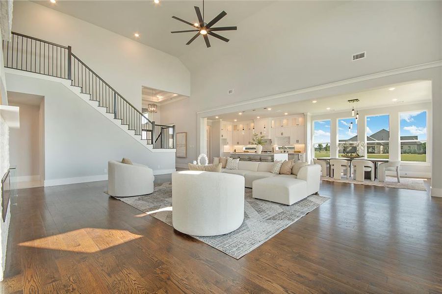 Living area featuring wood finished floors, high vaulted ceiling, recessed lighting, stairs, and a ceiling fan Living area featuring wood finished floors, high vaulted ceiling, recessed lighting, stairs, and a ceiling fan
