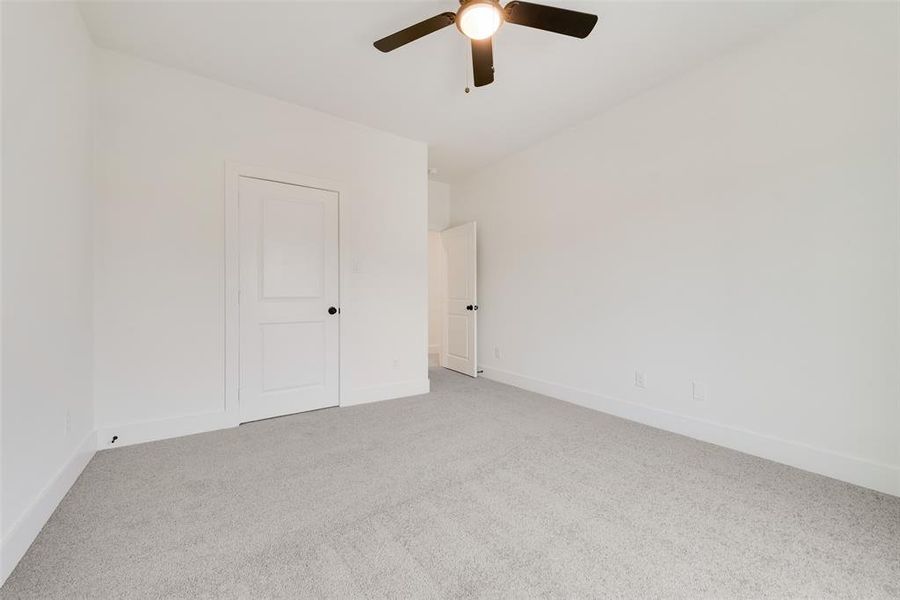 Spare room featuring light carpet, ceiling fan, and baseboards