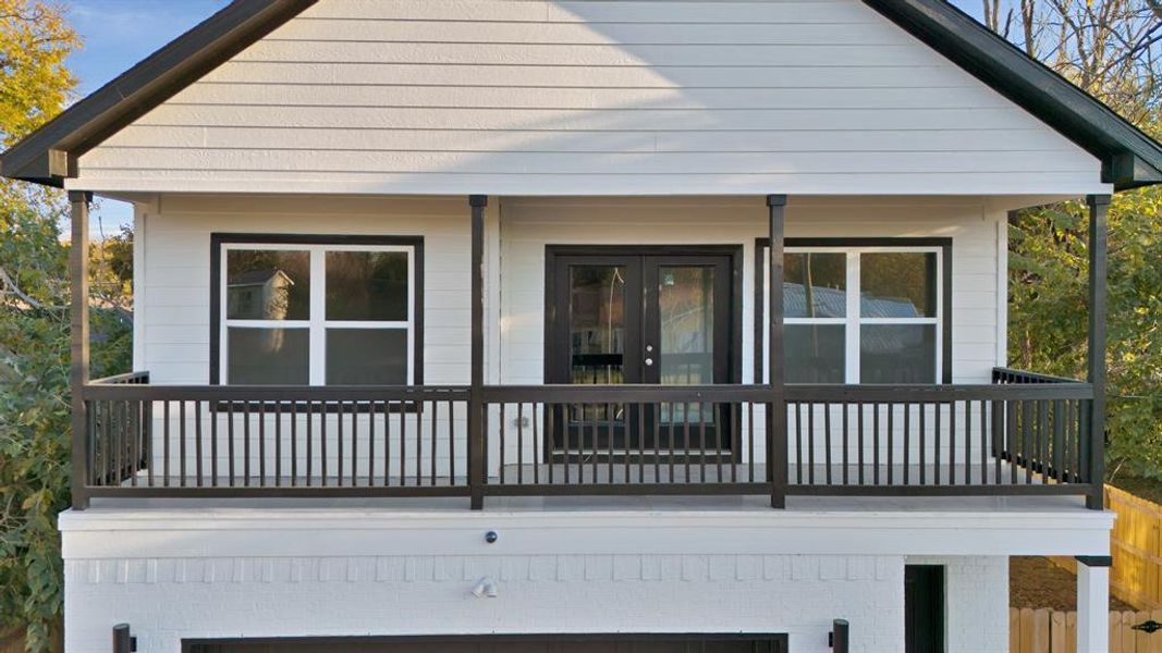 Rear view of house featuring french doors, a balcony, and a garage