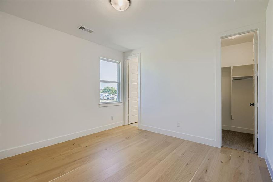 Unfurnished bedroom featuring light wood-style floors and a spacious closet