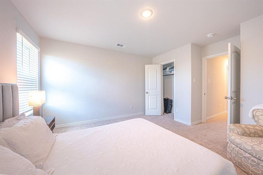 Bedroom with light colored carpet and a spacious closet
