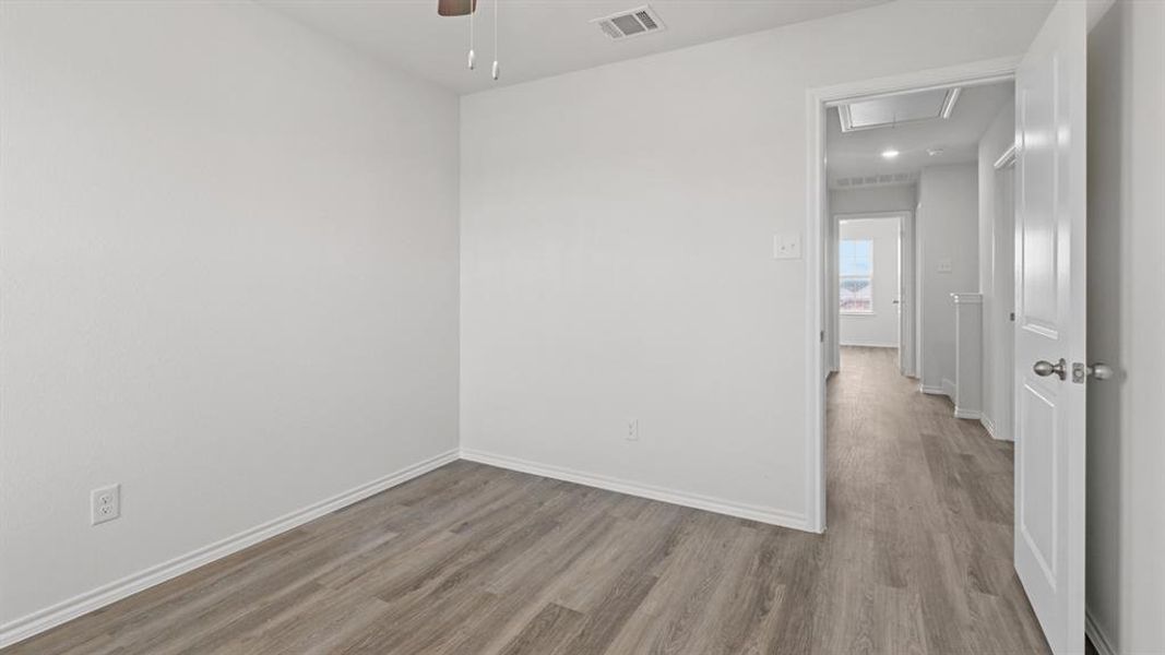 Room featuring wood-finish flooring, white walls, and white baseboards Room featuring wood-finish flooring, white walls, and white baseboards