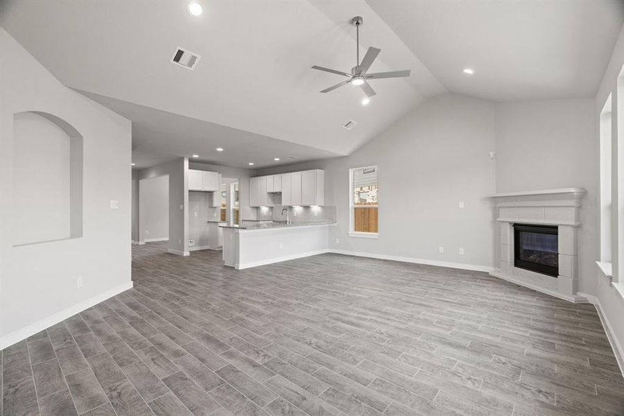 Family room flooded with natural light through the expansive windows.  The premium tile flooring adds a touch of luxury to the space, creating the perfect setting for relaxing moments and cherished gatherings with loved ones Sample photo, actual color and selections may vary.