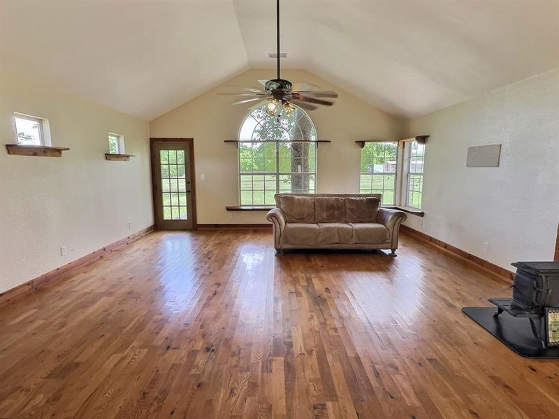 Living area featuring hardwood / wood-style floors, a wood stove, and a ceiling fan