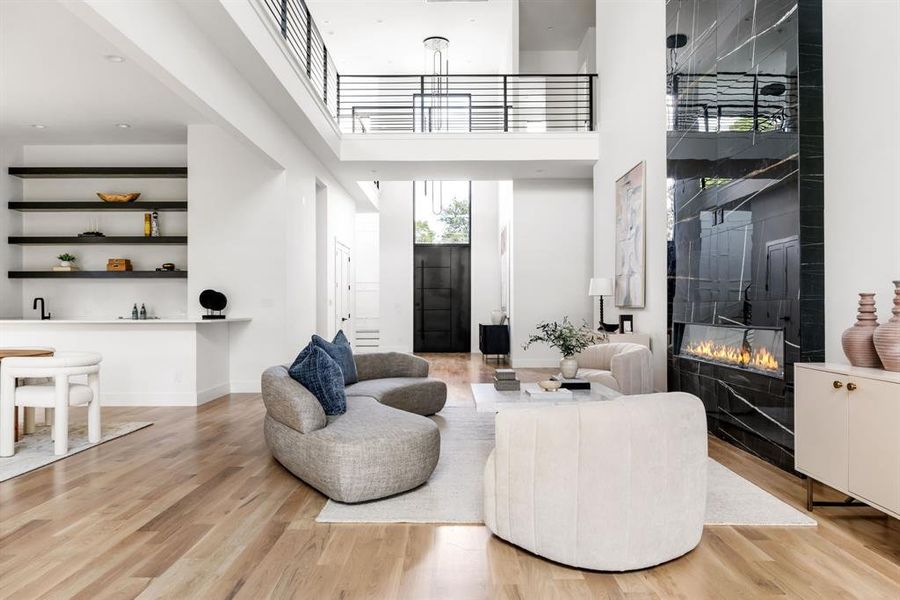 Living area featuring a towering ceiling, a premium fireplace, and light wood finished floors Living area featuring a towering ceiling, a premium fireplace, and light wood finished floors
