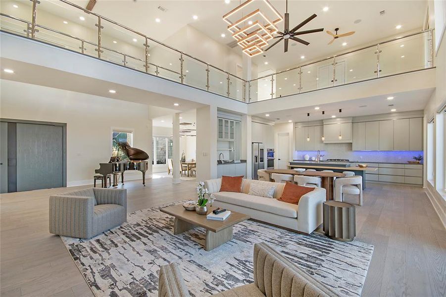 Living area with ceiling fan, light wood-style floors, recessed lighting, and a high ceiling Living area with ceiling fan, light wood-style floors, recessed lighting, and a high ceiling