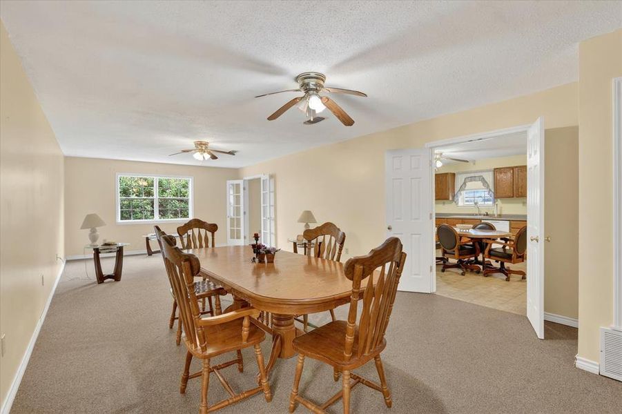 Spacious room featuring neutral carpeting, light-toned walls, and multiple ceiling fans