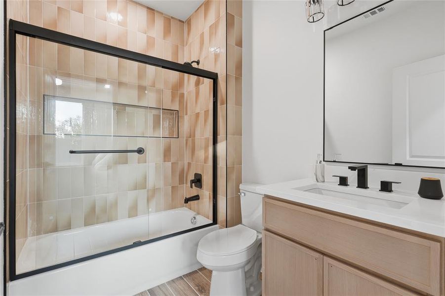 Bathroom featuring a tiled shower/tub combination with a clear glass enclosure and matte black fixtures Bathroom featuring a tiled shower/tub combination with a clear glass enclosure and matte black fixtures