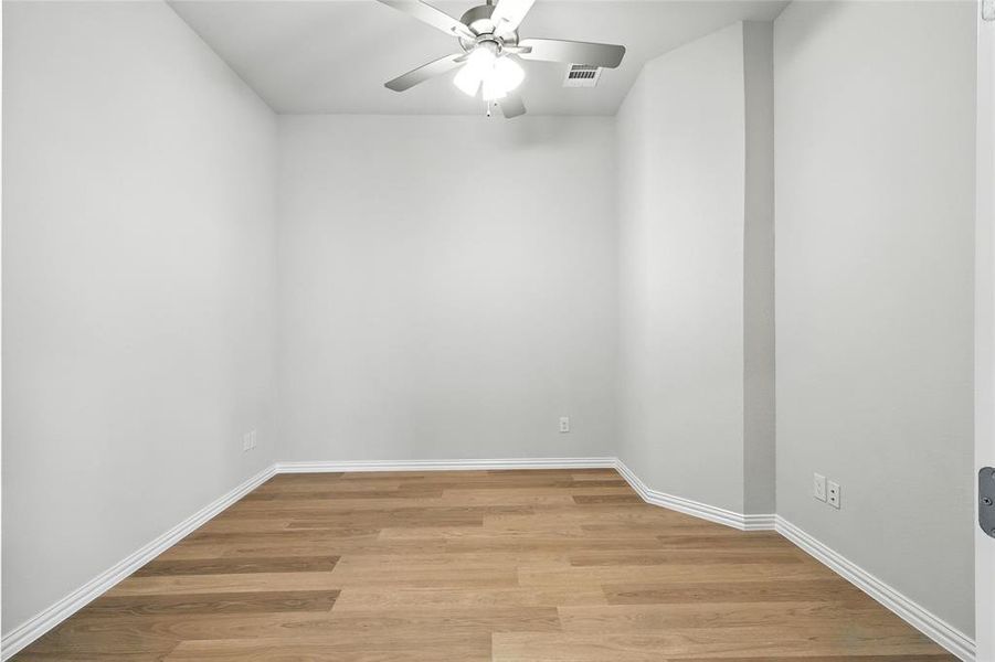 Empty room with a ceiling fan and light wood-style flooring Empty room with a ceiling fan and light wood-style flooring