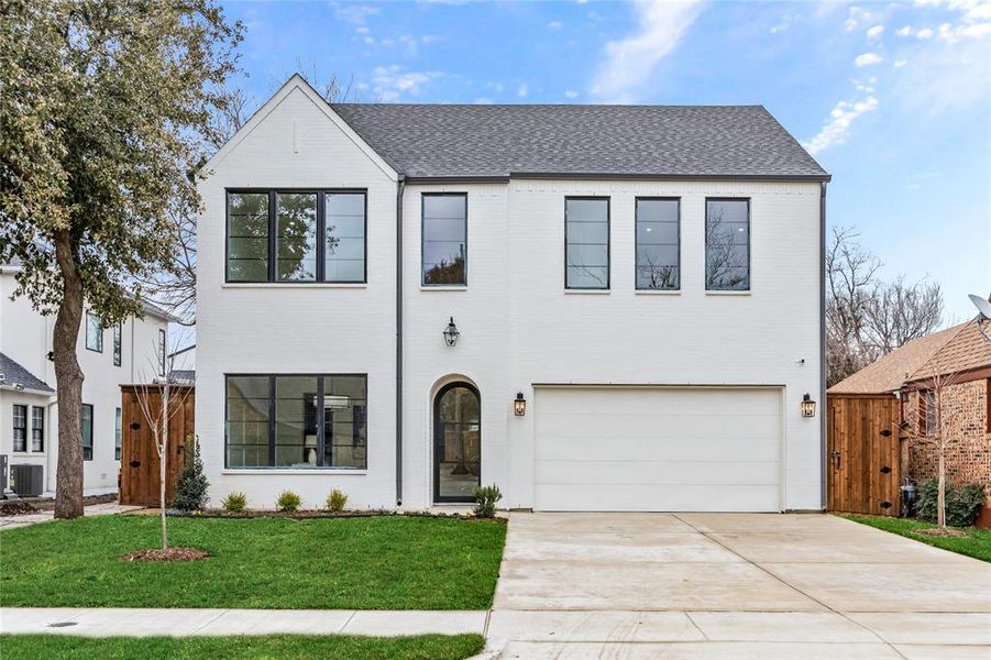 View of front of property featuring a garage, central AC unit, and a front yard