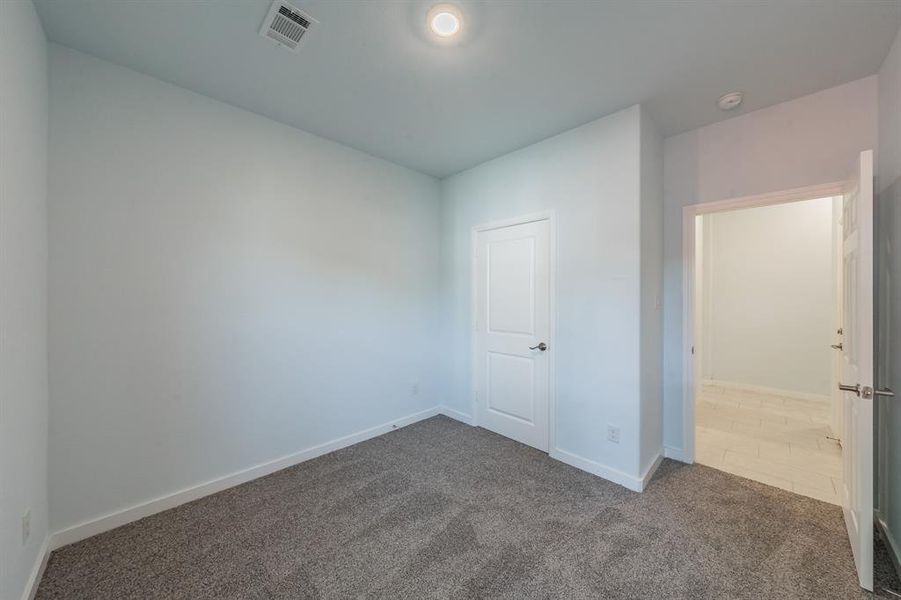 Unfurnished bedroom with dark colored carpet and baseboards Unfurnished bedroom with dark colored carpet and baseboards