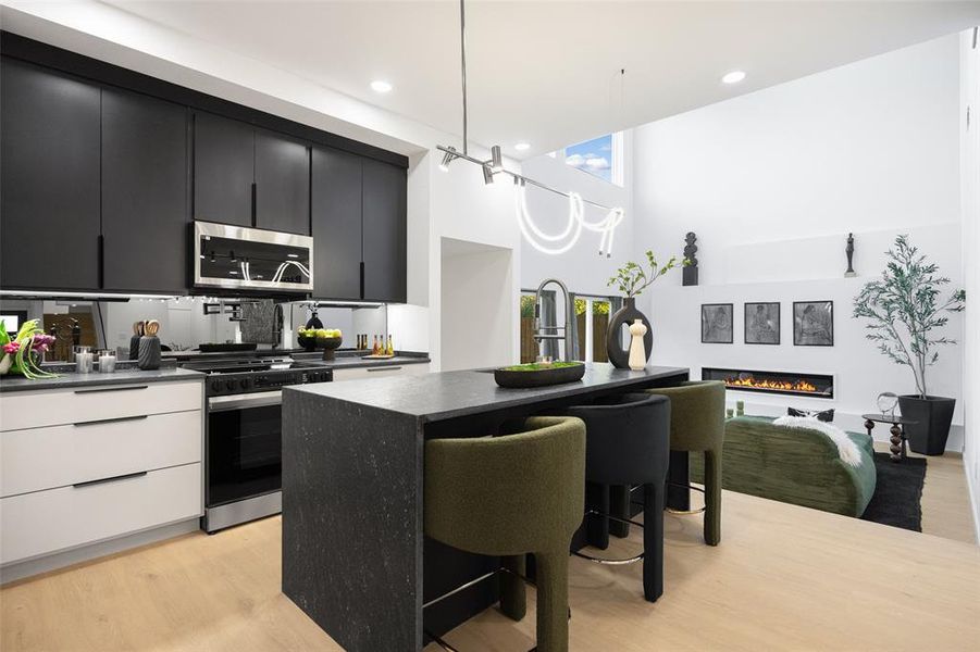 Kitchen with dark cabinets, a breakfast bar, an island with sink, modern cabinets, and slide in range oven