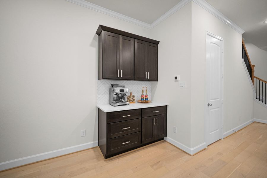 A dedicated coffee bar with upper and lower cabinetry, quartz counters, and herringbone tile — the pantry door is just to the right, keeping everything within reach. A dedicated coffee bar with upper and lower cabinetry, quartz counters, and herringbone tile — the pantry door is just to the right, keeping everything within reach.