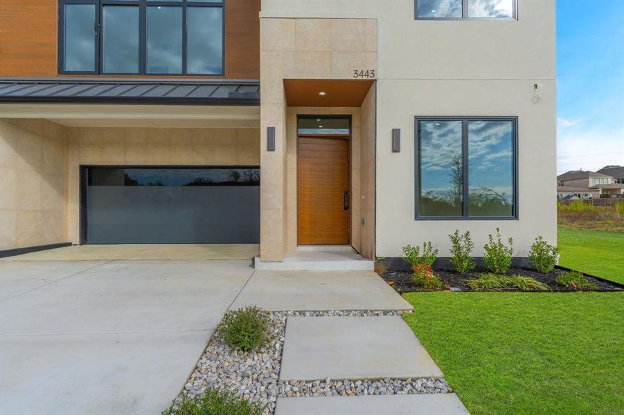 View of exterior entry with a standing seam roof, a garage, a metal roof, and driveway View of exterior entry with a standing seam roof, a garage, a metal roof, and driveway