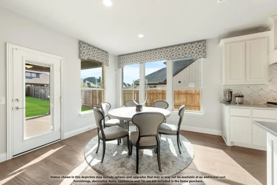 Bright dining area with round white table, gray chairs, hardwood floors, and large windows with backyard view.