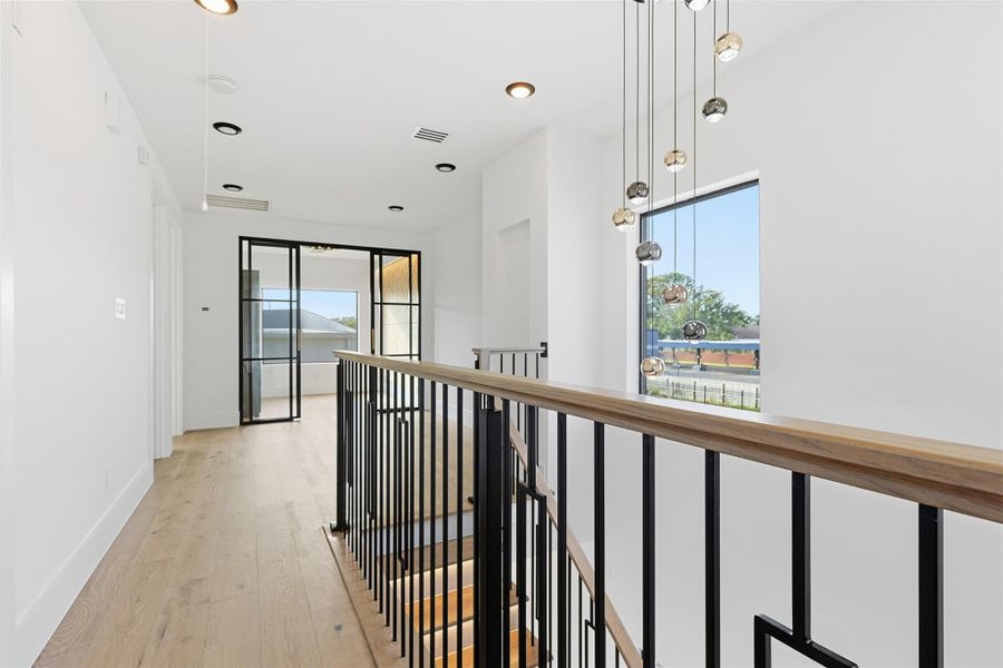 Same floorplan - different finishes. The second-floor landing is highlighted by a multi-port globe chandelier and a contemporary iron railing overlooking the staircase.