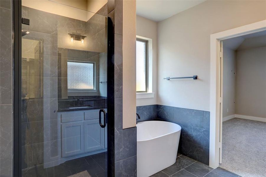 Full bath featuring a freestanding tub, a stall shower, vanity, tile walls, and dark tile patterned floors Full bath featuring a freestanding tub, a stall shower, vanity, tile walls, and dark tile patterned floors