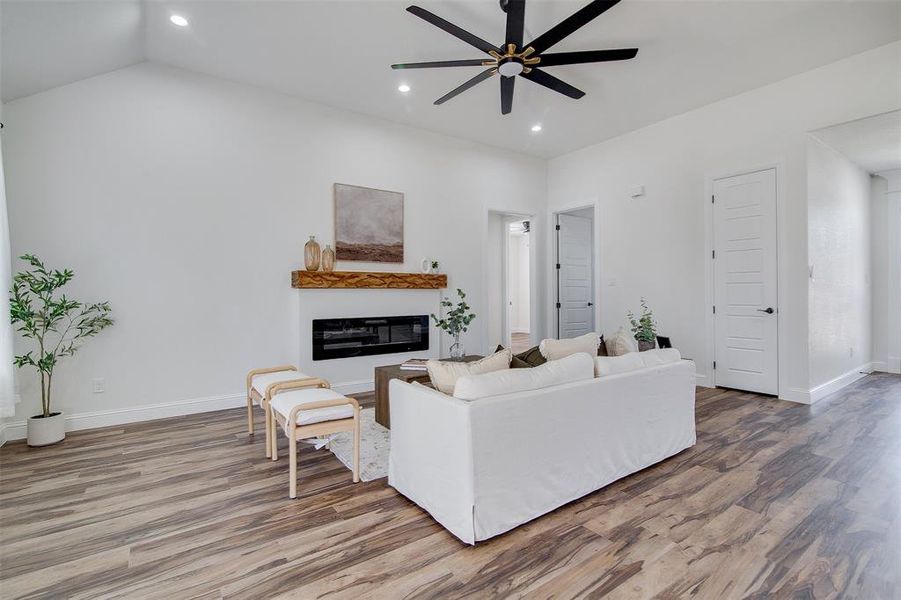 Living room with ceiling fan, wood-type flooring, and lofted ceiling