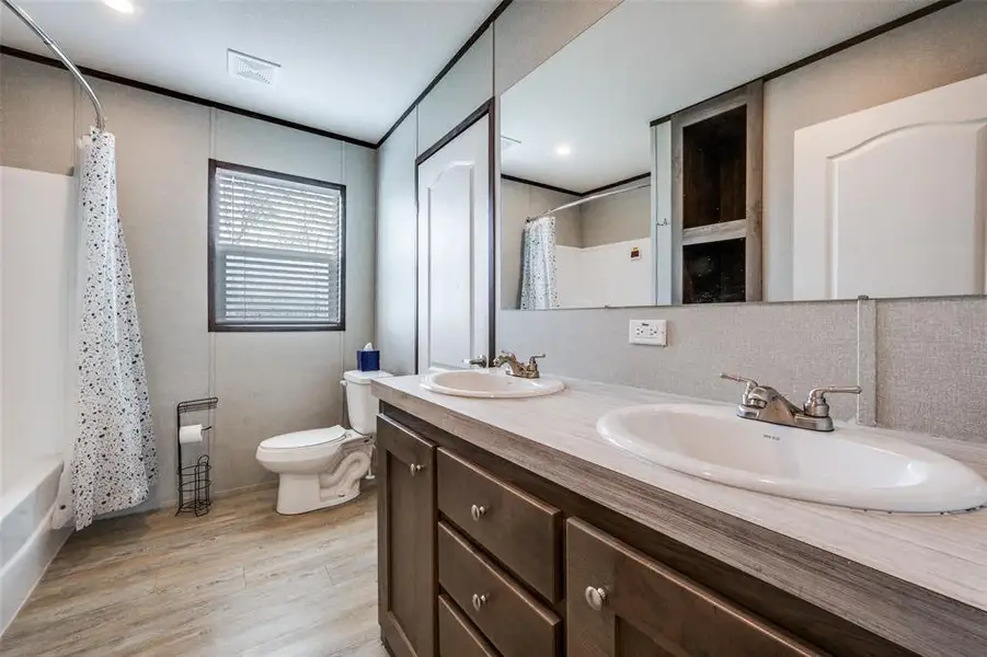 Bathroom with double vanity, shower / bath combination with curtain, and light wood-style flooring Bathroom with double vanity, shower / bath combination with curtain, and light wood-style flooring