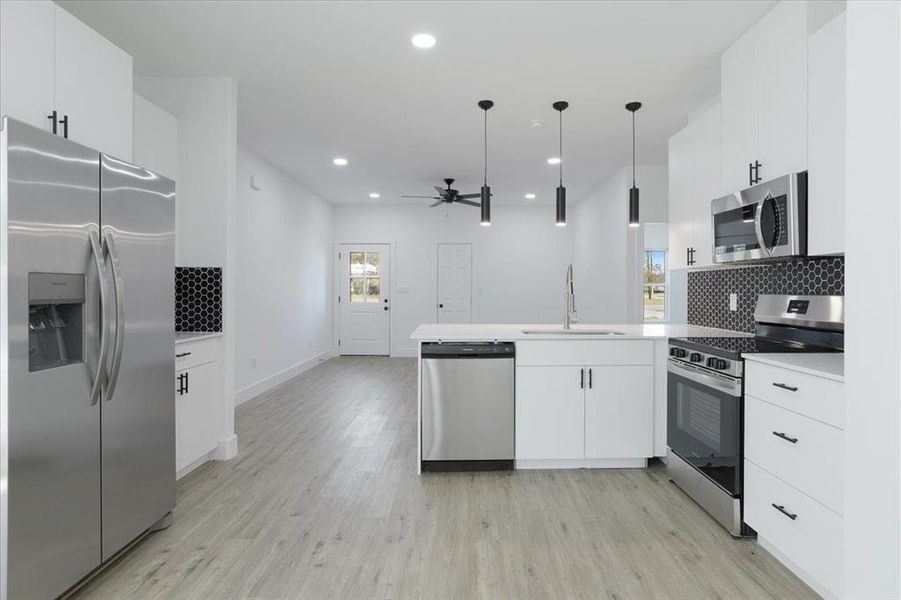 Kitchen featuring ceiling fan, sink, hanging light fixtures, stainless steel appliances, and kitchen peninsula