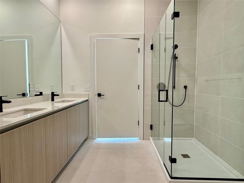 A sleek, contemporary bathroom with a dual vanity and a frameless glass shower.