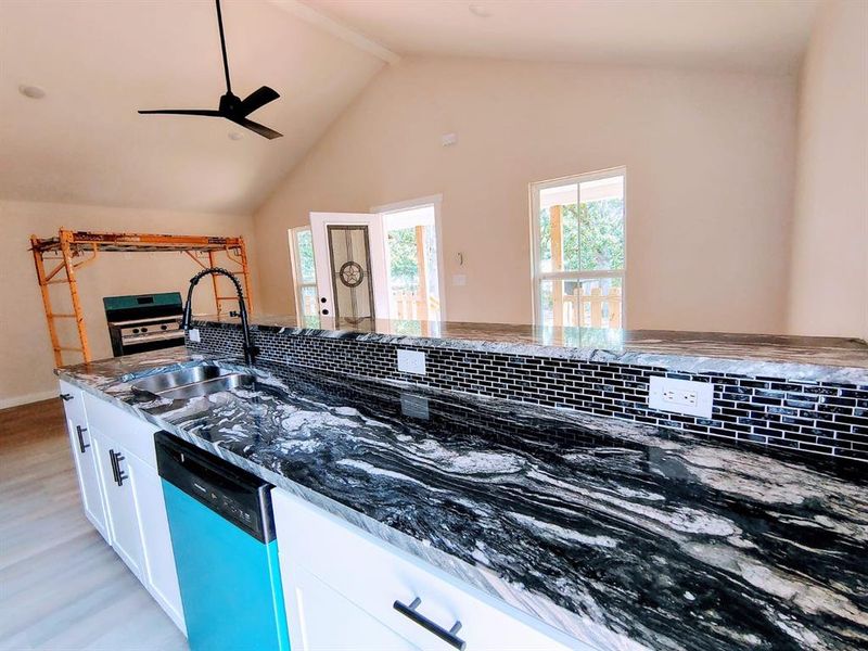Kitchen featuring dishwashing machine, dark stone countertops, light wood-style flooring, white cabinetry, and a ceiling fan
