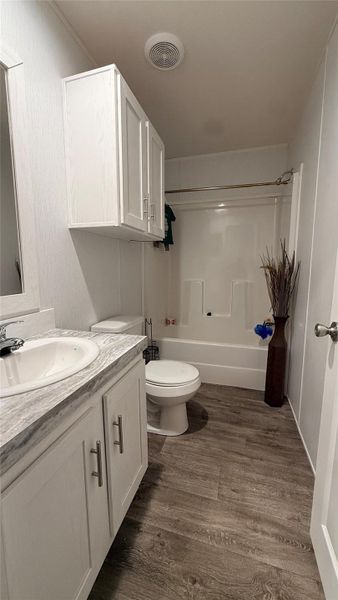 Functional bathroom featuring wood-look flooring and clean white cabinetry. Functional bathroom featuring wood-look flooring and clean white cabinetry.