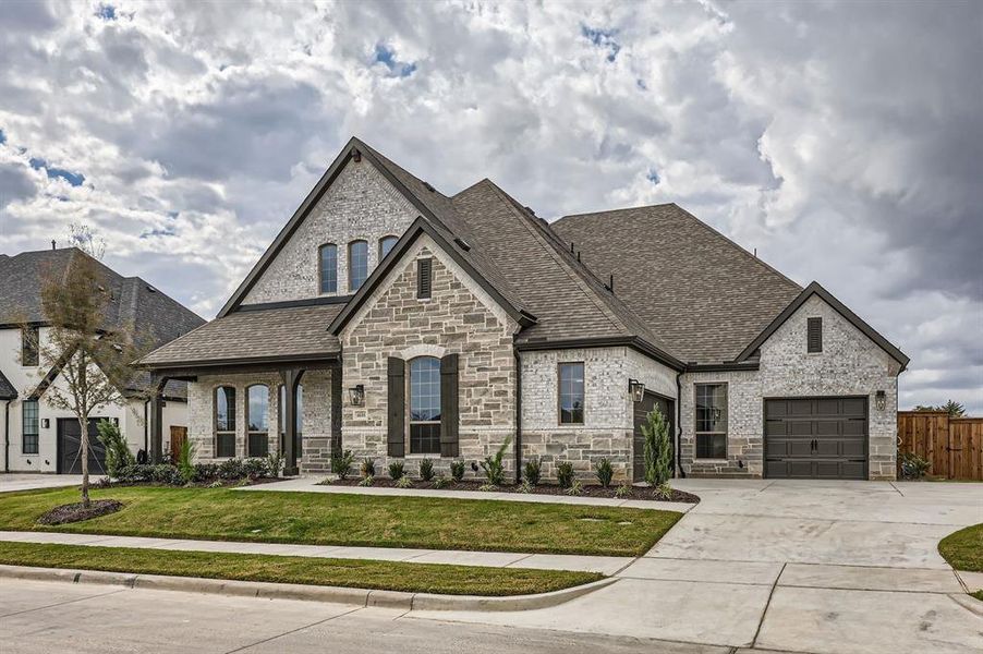 French provincial home with a front yard and a garage