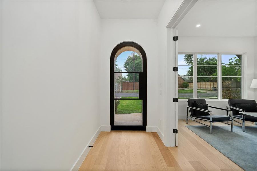 Entryway featuring light hardwood flooring and an arched glass panel door