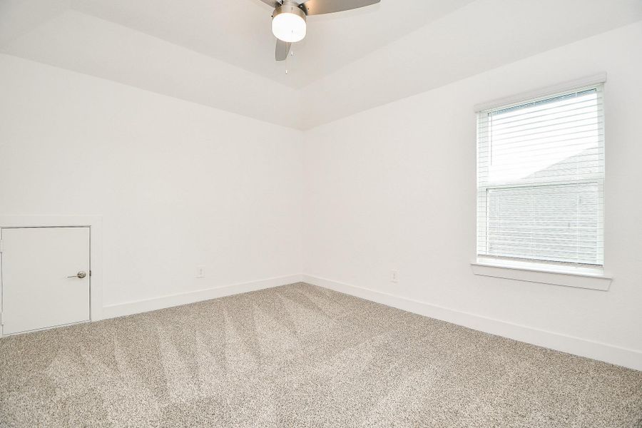A spacious secondary room with neutral carpet, a ceiling fan, and a window with 2" blinds that allow for natural light. A spacious secondary room with neutral carpet, a ceiling fan, and a window with 2" blinds that allow for natural light.