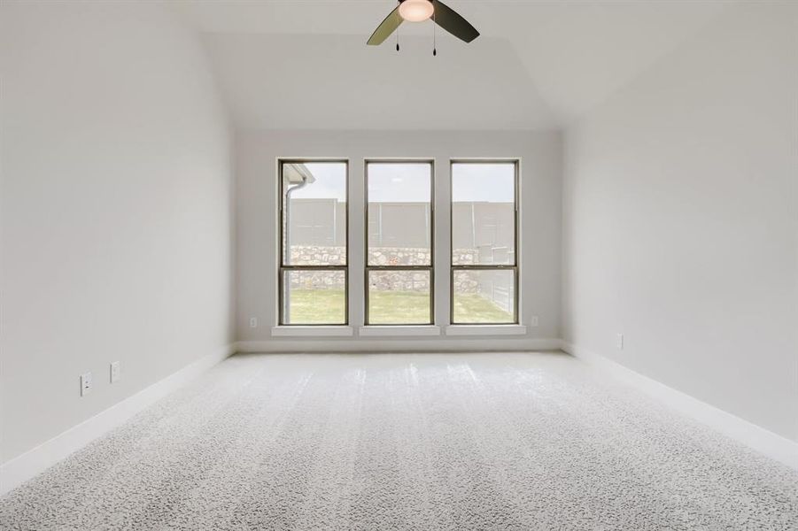Spacious main bedroom room featuring vaulted ceilings, a contemporary ceiling fan, and light-toned carpet flooring