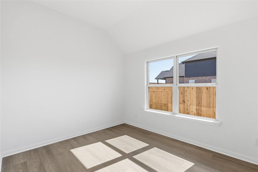 Unfurnished room featuring vaulted ceiling and wood finished floors