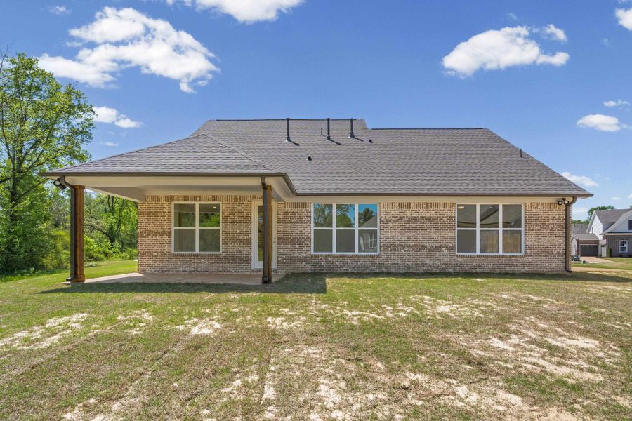 Back of house featuring a patio, a lawn, brick siding, and roof with shingles