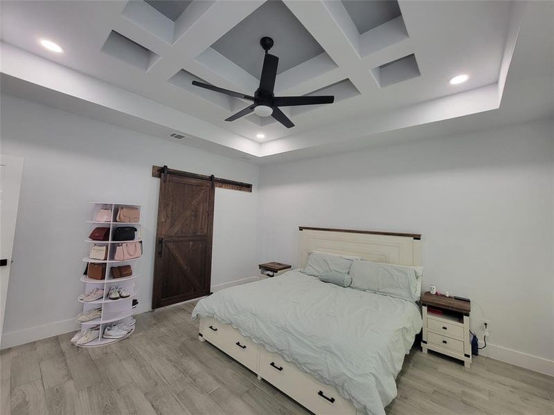 Primary Bedroom with coffered ceiling, recessed lighting, light wood finished floors, a barn door, and a ceiling fan