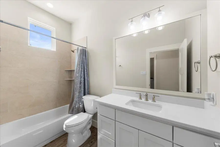 Bathroom with vanity, shower / bath combo with shower curtain, and wood finished floors Bathroom with vanity, shower / bath combo with shower curtain, and wood finished floors