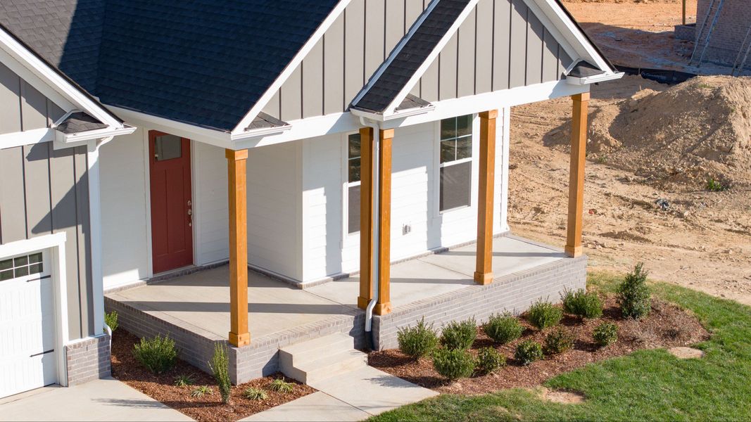 Exterior of home with white and gray siding and wood accent columns around covered front porch