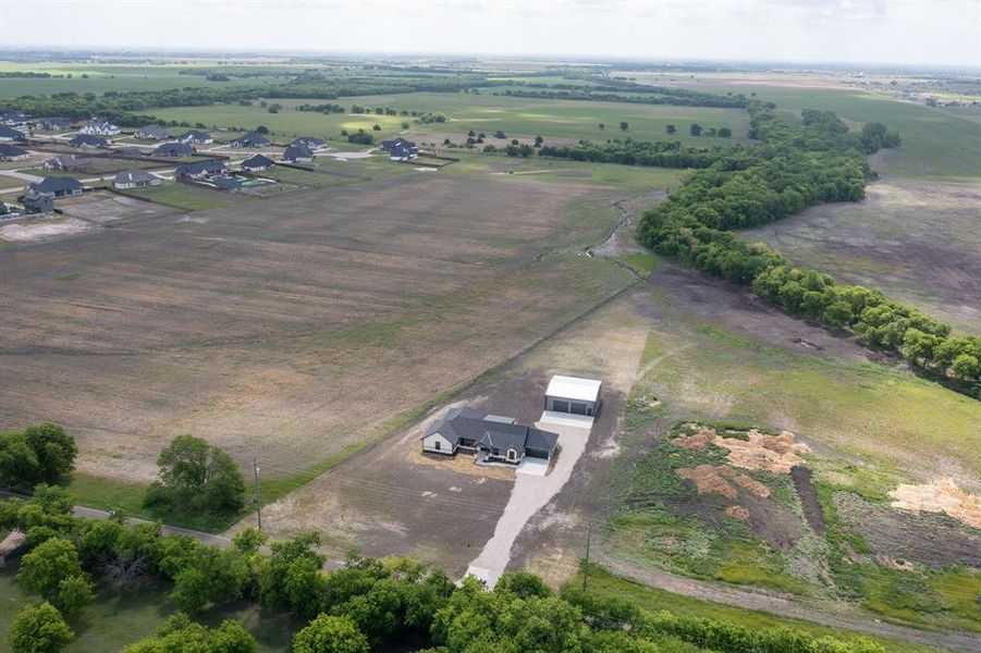 Aerial view of the property, showcasing a single-story home with an expansive surrounding landscape