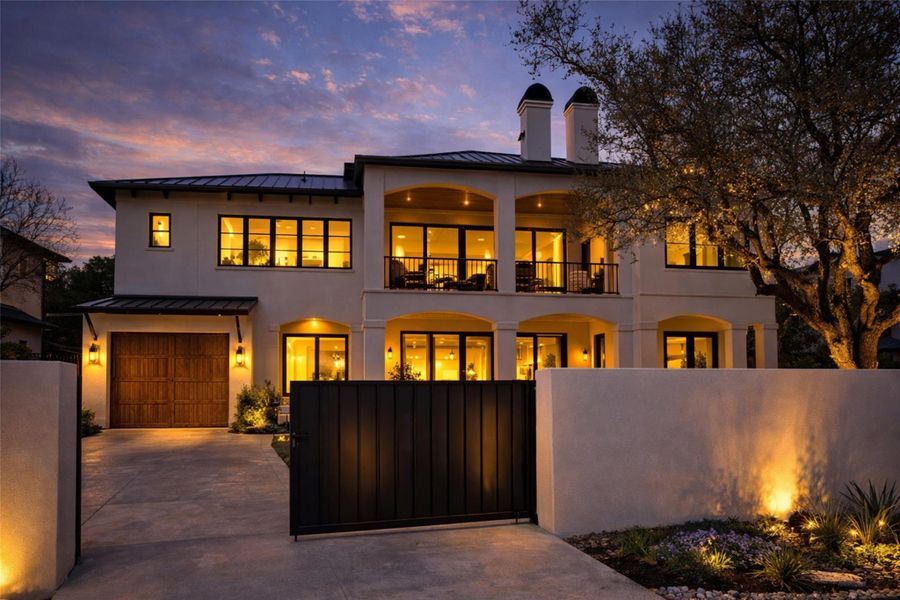 Rear view of house with a standing seam roof, a balcony, a garage, and stucco siding