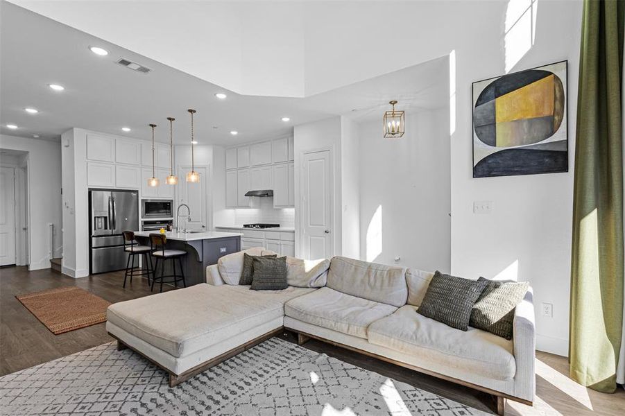 Living room with dark wood-type flooring, recessed lighting, and a chandelier