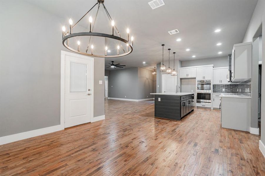 Kitchen featuring double oven, light countertops, white cabinetry, open floor plan, and visible vents Kitchen featuring double oven, light countertops, white cabinetry, open floor plan, and visible vents