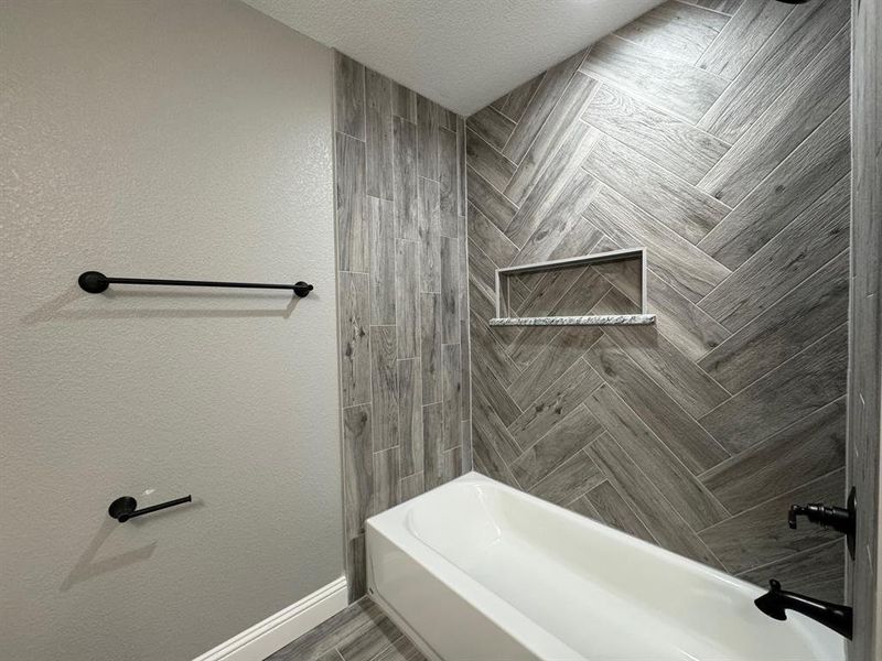 Bathroom with shower / tub combination and a textured ceiling