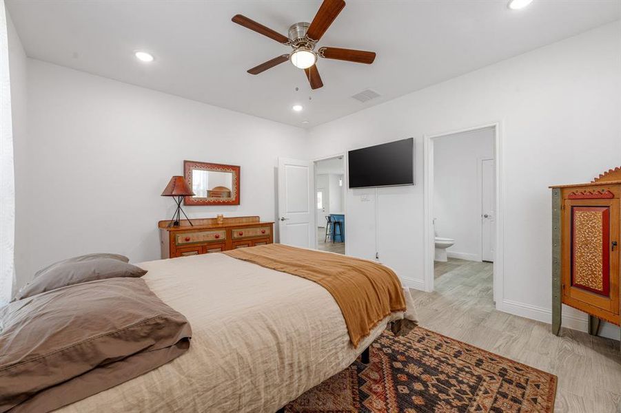 Bedroom with recessed lighting, light wood-style floors, ceiling fan, and connected bathroom