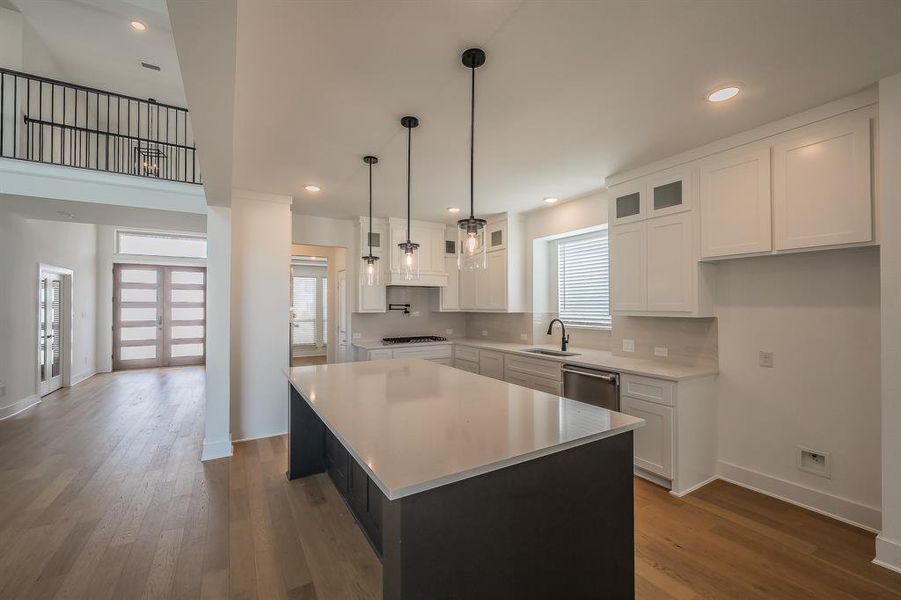 The kitchen features a large island with a light-colored countertop, white cabinetry, and stainless steel appliances