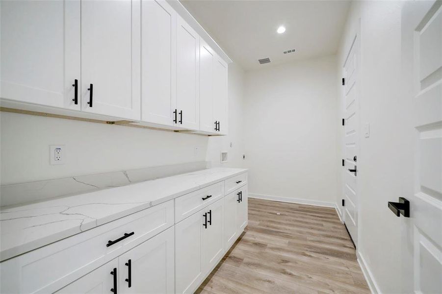 A bright utility room featuring with matching cabinets and countertops, creating a clean and modern aesthetic.